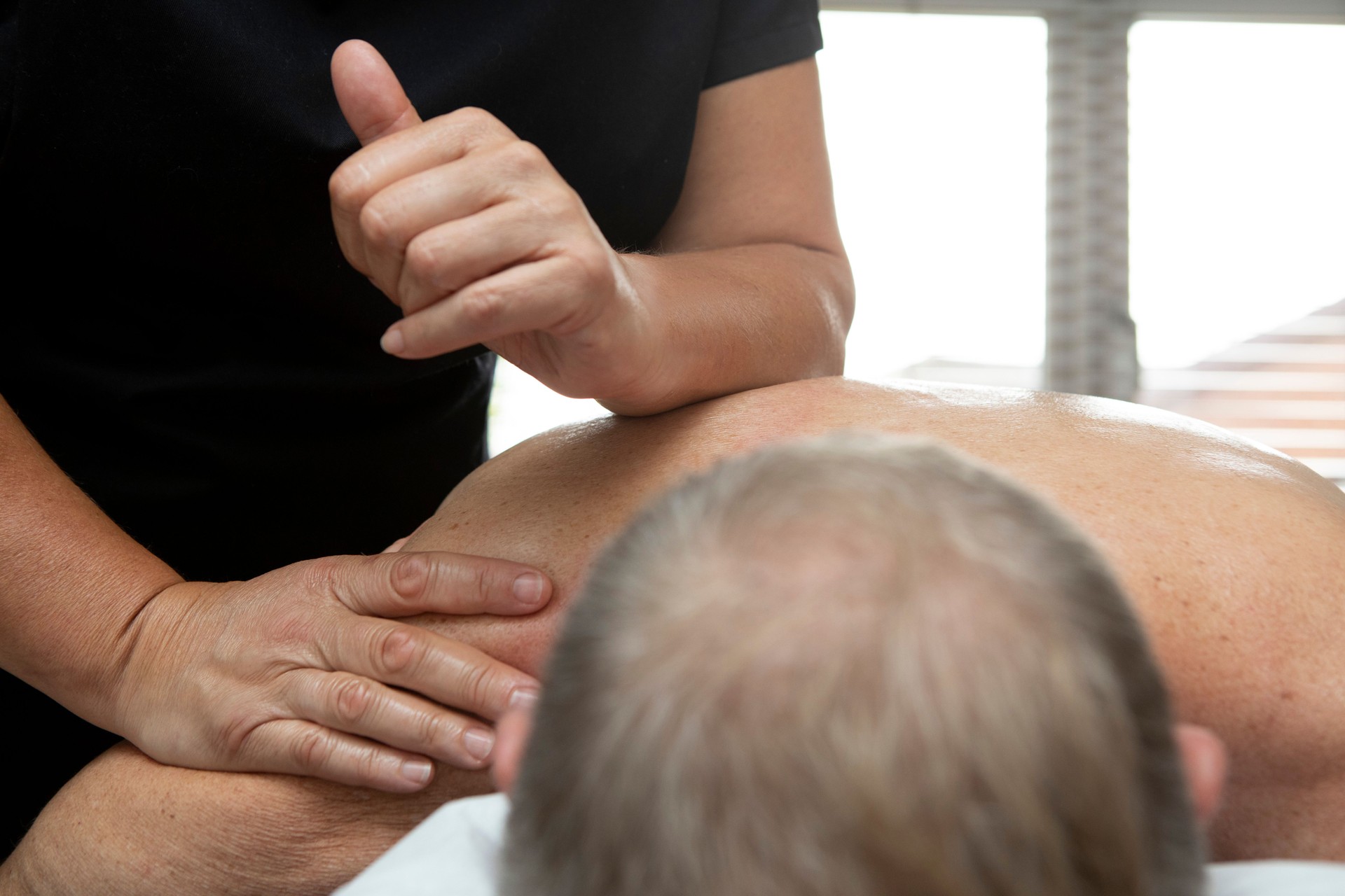 Female hands and arms giving a deep tissue massage to a man lying face down